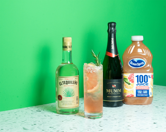 A bottle of tequila, a bottle of sparkling wine, a bottle of grapefruit juice and a cocktail on a green background