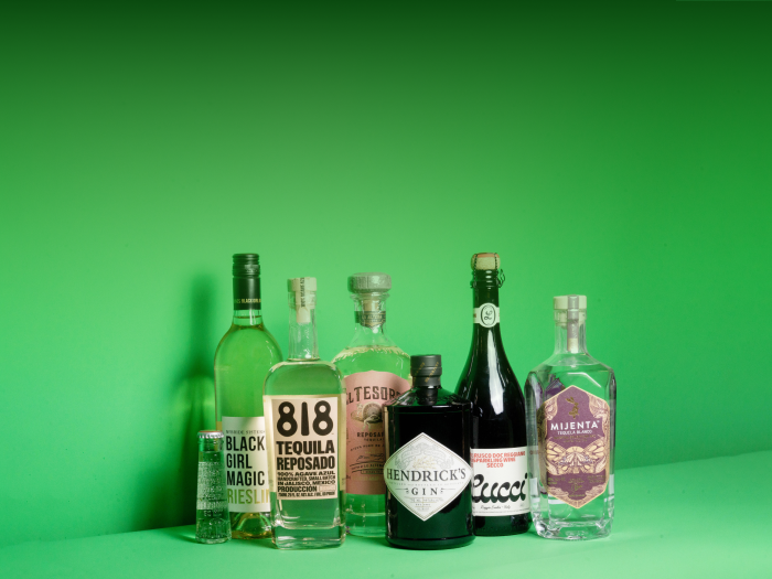 Various bottles of alcohol from women led brands on a green background.